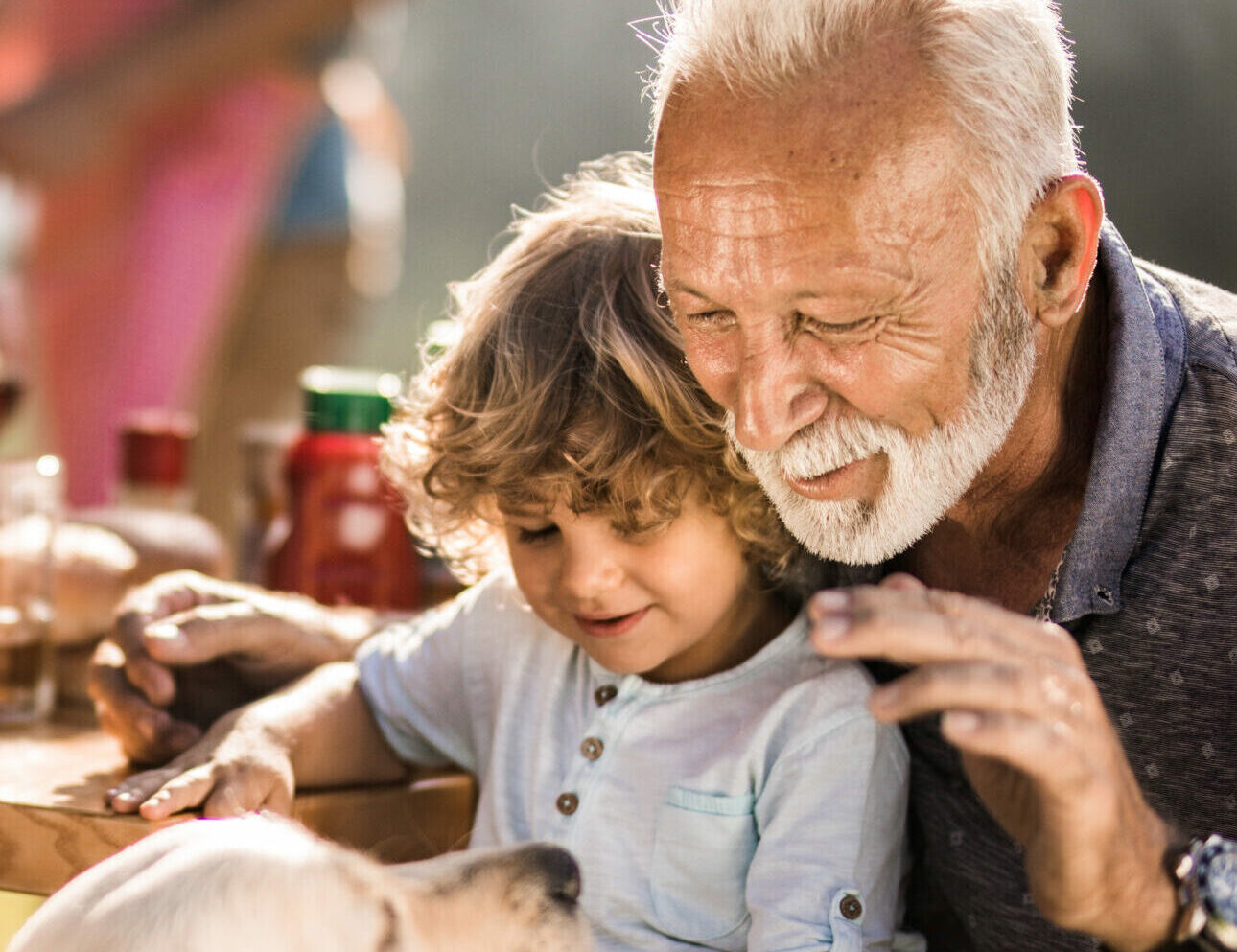 Mature man and his small grandchild enjoying on a picnic lunch with their dog.